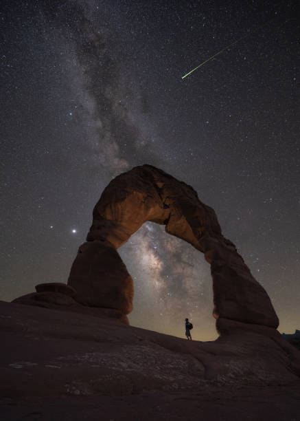 istock Hiker standing under a lit delicate arch in Moab Utah 1271556732