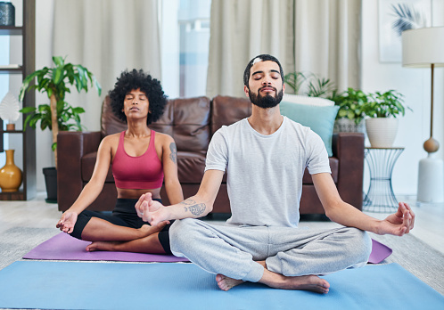 Shot of a young couple practising yoga in their living room