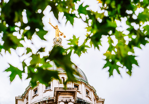 The gilded statue of Lady Justice holding a sword and balancing scales, on top of the Old Bailey, England's criminal court in the City of London, officially called the Central Criminal Court.