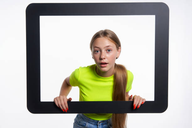 istock Teen girl peeking through digital tablet frame 1271561438