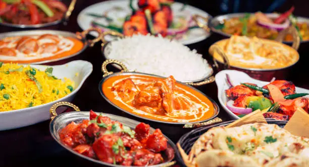 This image shows Assorted Indian recipes food various with spices and rice on wooden table