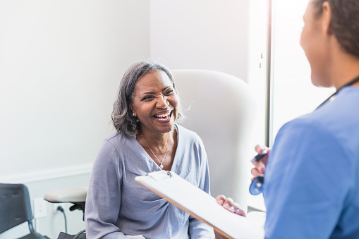 A beautiful senior woman shares a lighthearted moment while talking with a female healthcare professional.