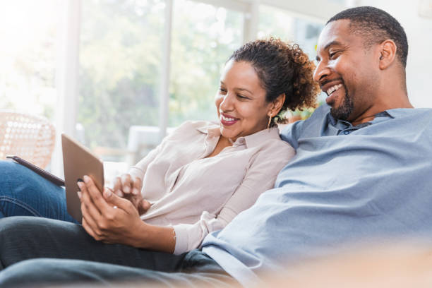 istock Couple relaxes on sofa to watch video on tablet 1271562721