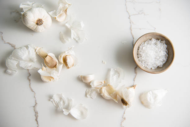 Garlic cloves and salt on marble white top