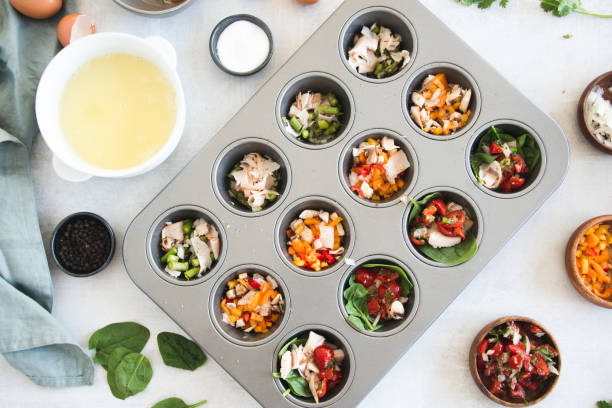 Flat lay of muffin tin with vegetables and meat to prepare mini egg white quiches Flat lay of muffin tin with vegetables and meat to prepare mini egg white quiches muffin tin eggs stock pictures, royalty-free photos & images