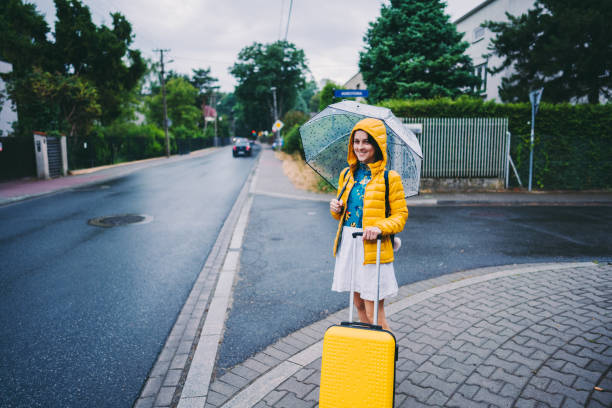 Portrait of smiling woman with suitcase at rainy day