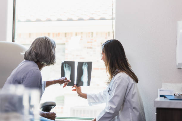 старшая женщина беседует с врачом о рентгене ног - x ray image radiologist examining using voice стоковые фото и изображения