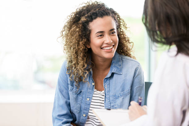 Smiling female patient receives good news A smiling female patient attentively listens as a doctor gives her good news. womens issues photos stock pictures, royalty-free photos & images