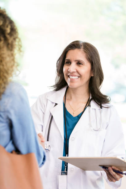 confident female doctor greets female patient - doctor patient greeting talking imagens e fotografias de stock