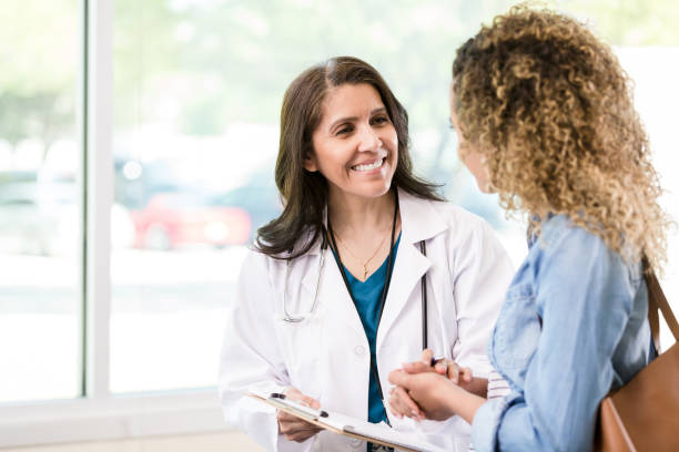 Caring mature female doctor A caring mature female doctor smiles as she gives good news to a female patient about the patient's test results. womens issues photos stock pictures, royalty-free photos & images