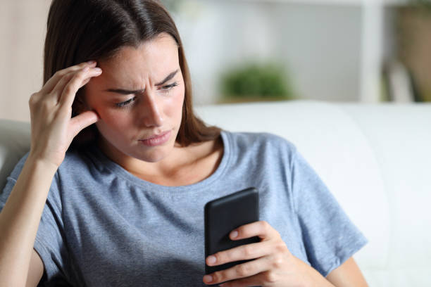 chica preocupada revisando el teléfono inteligente en casa - people worried confusion women fotografías e imágenes de stock