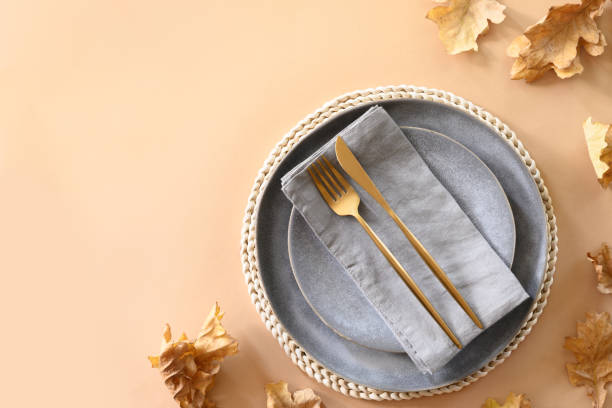 istock Fall table setting with autumn oak leaves and golden cutlery on grey background. View from above, space for design. 1271565220