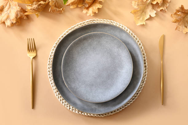 istock Fall table setting with autumn oak leaves and golden cutlery on grey background. View from above. 1271565229