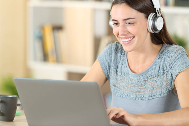 istock Happy student with headphones and laptop e-learning 1271565391