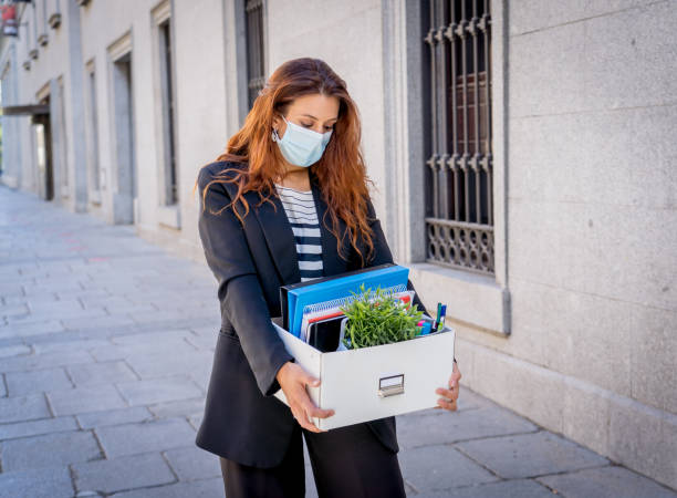 sad businesswoman in medical protective mask in business district with box of office staff feeling depressed due to job loss. coronavirus job cuts, covid-19 unemployment and economic crisis concept. - cheap finance cutting downsizing imagens e fotografias de stock