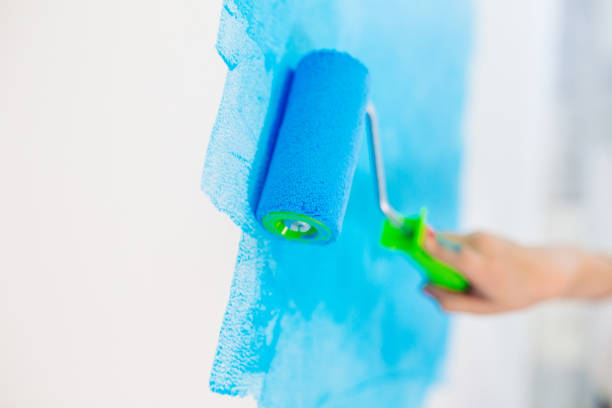 istock blue color painting wall with roller in hand. 1271567967