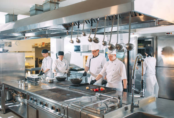 Five chefs wearing uniforms posing in a kitchen. stock photo