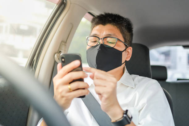 istock Business man with face mask and glasses using mobile smartphone in car. 1271569323