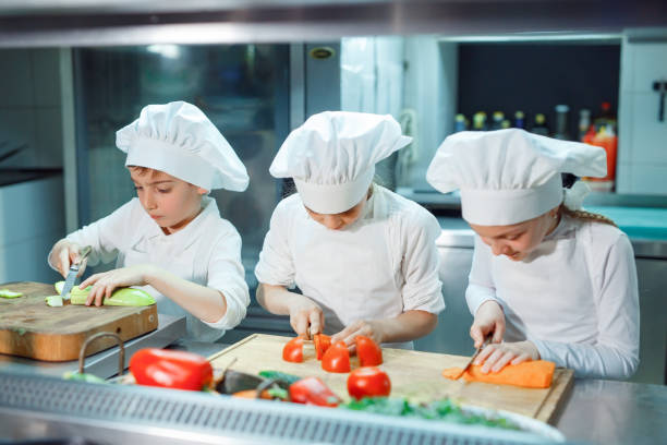 istock Children in chef's hat grind vegetables on the kitchen. 1271569514