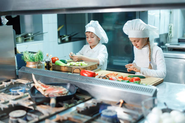 istock Children in chef's hat grind vegetables on the kitchen. 1271569547