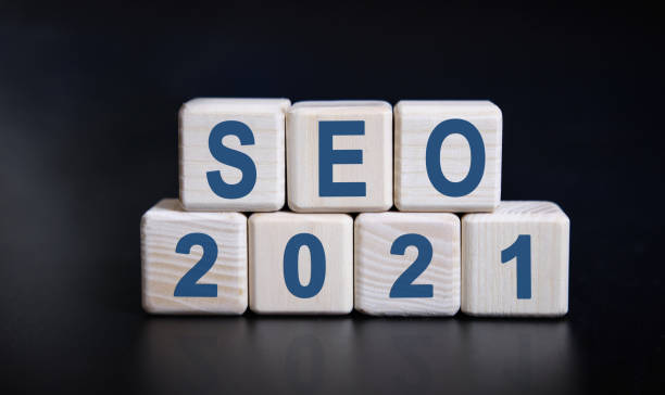 istock SEO 2021 text on wooden cubes on a black background with reflection. 1271571144