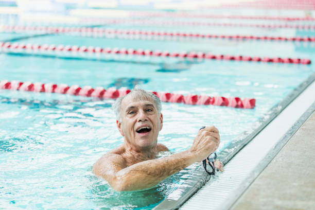 istock Senior man in pool taking break from swimming laps 1271575696