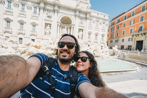 Young couple is taking a selfie near the Trevi Fountain in Rome, Italy
