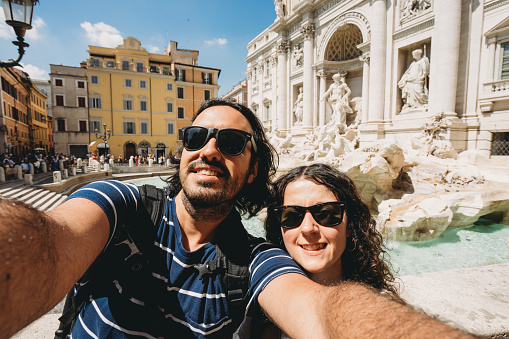 Young couple is taking a selfie near the Trevi Fountain in Rome, Italy
