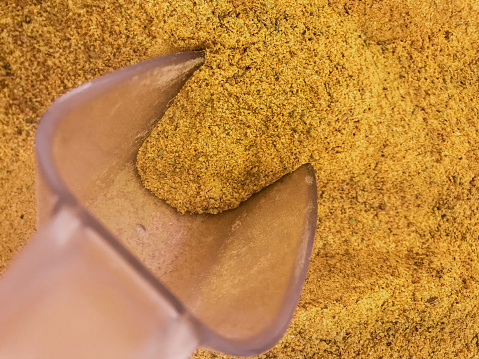 Yellow curry spice background with scoop for sale powder by weight