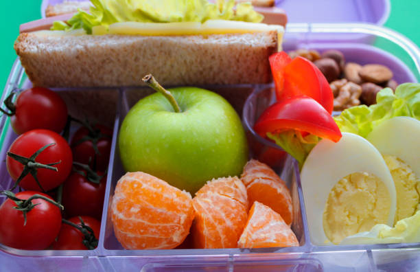 fermez-vous vers le haut de la boîte à lunch de lilas avec la nourriture utile pour le déjeuner et la collation : sandwich, légumes, fruits, noix et oeufs. concept d’aliments sains, collation pour adultes et enfants - lunch box lunch red apple photos et images de collection