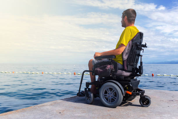 istock Man sitting in a wheelchair on the beach 1271588559