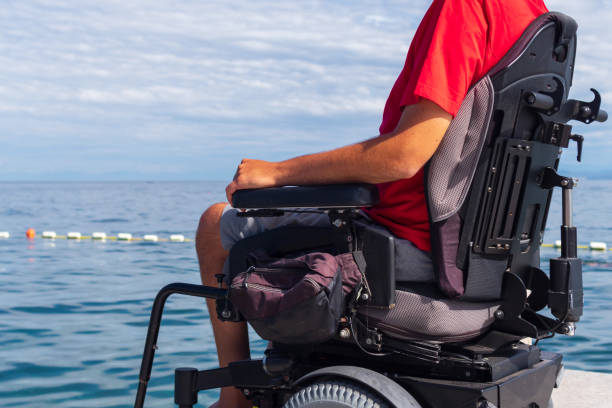 istock Man sitting in a wheelchair on the beach 1271588560