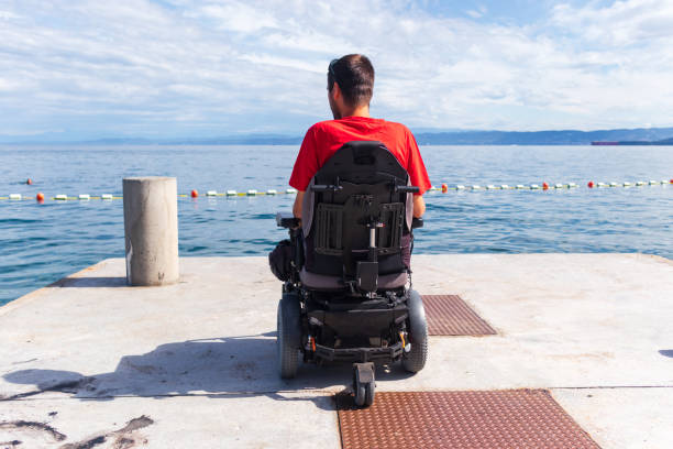 istock Man sitting in a wheelchair on the beach 1271588567