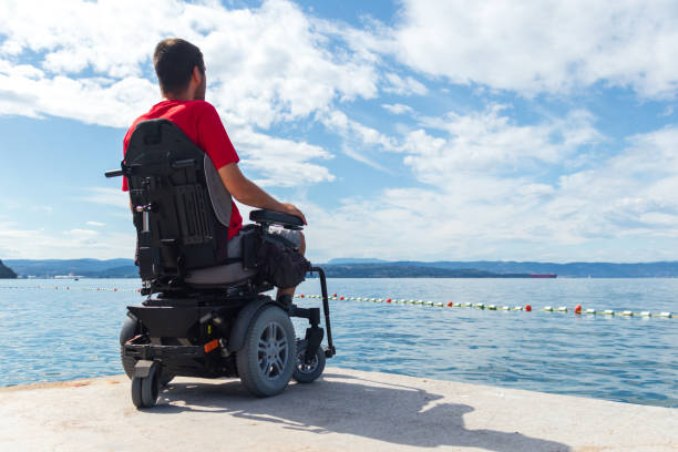 istock Man sitting in a wheelchair on the beach 1271588573