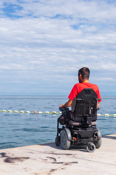 istock Man sitting in a wheelchair on the beach 1271588576
