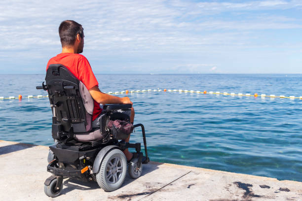 istock Man sitting in a wheelchair on the beach 1271588578
