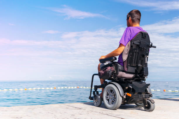 hombre en silla de ruedas en la playa - cuadriplégico fotografías e imágenes de stock