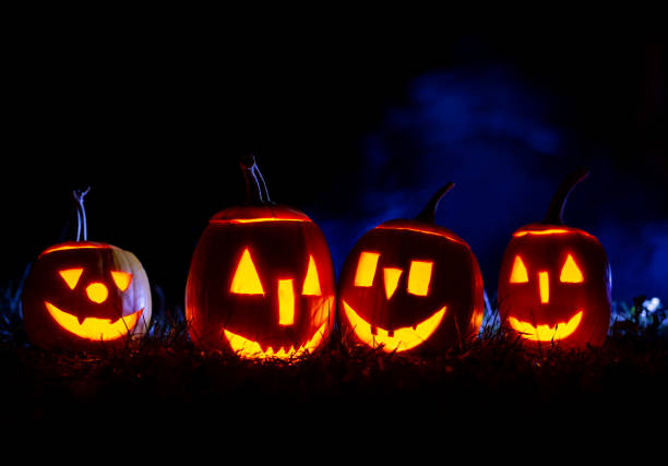 istock Iluminated horror pumpkins over blue background with smoke. 1271593990