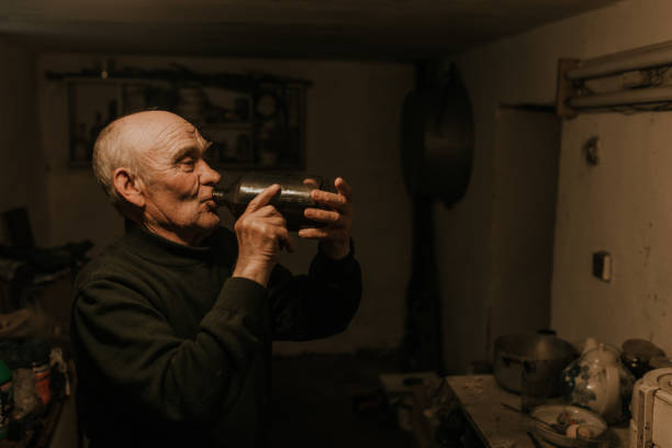 istock old man drinks wine from a glass bottle in the dark basement 1271600335