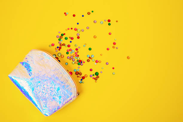 istock Creative composition with shiny multicolored plastic and glass gems and beads spilled out from leather cosmetic bag of mother-of-pearl color, top view, copy space for advertisement 1271601055