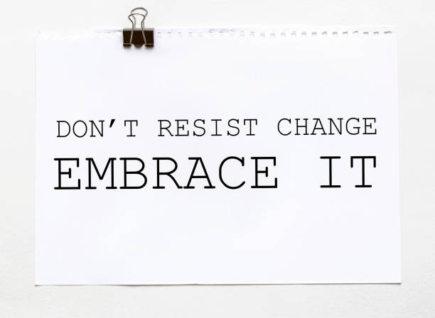 white paper with text Do Not Resist Change Embrace It on a white background with stationery