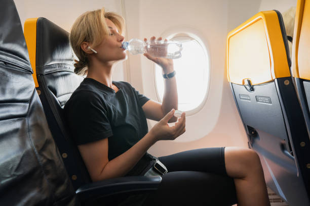 istock Woman drinks water during her flight in an airplane 1271605156