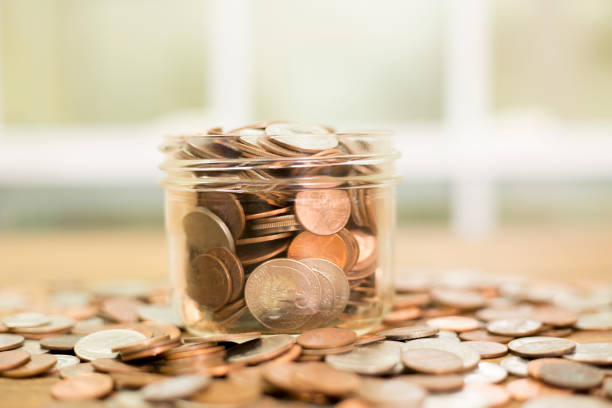 istock US coins overflow from glass jar. 1271607070