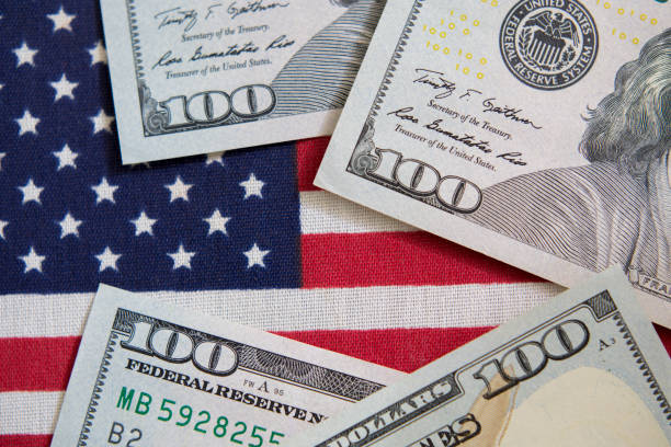 istock $100 dollar bills and American Flag. 1271607167