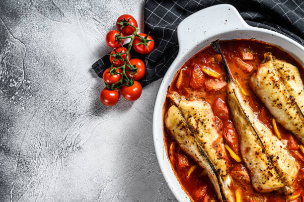 istock Monkfish baked in tomatoes in a baking dish. Black background. Top view. Copy space 1271612360