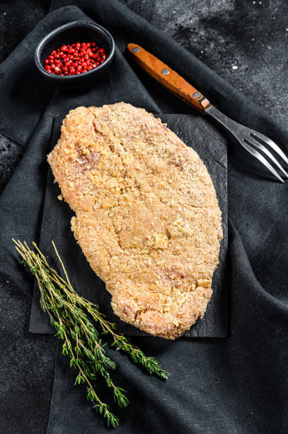 homemade raw breaded german weiner schnitzel.  black background. top view - weiner schnitzel imagens e fotografias de stock