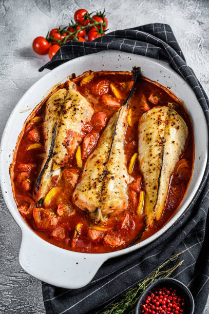 istock Cooking in tomatoes monkfish fish in a baking dish. Fresh seafood. Gray background. Top view 1271612834