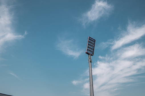 Tall stadium reflector and blue cloudy sky on sunny day