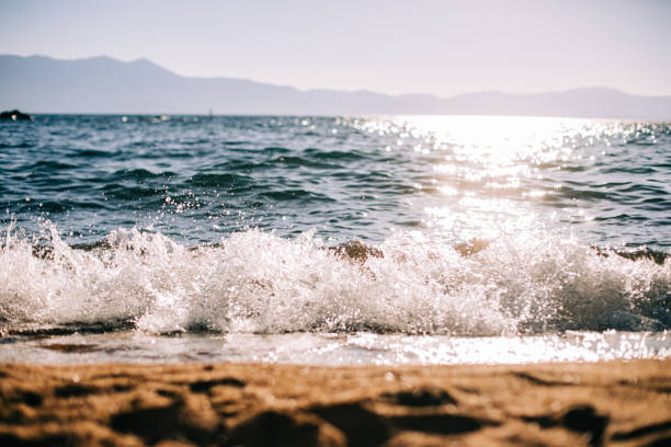 istock Splashing Wave on Sandy Shore with Sparkling Sunshine on Water 1271617562