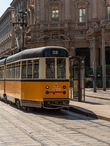 eine gelbe straßenbahn fährt durch die straßen der stadt mailand - milan italy cable car old italy stock-fotos und bilder